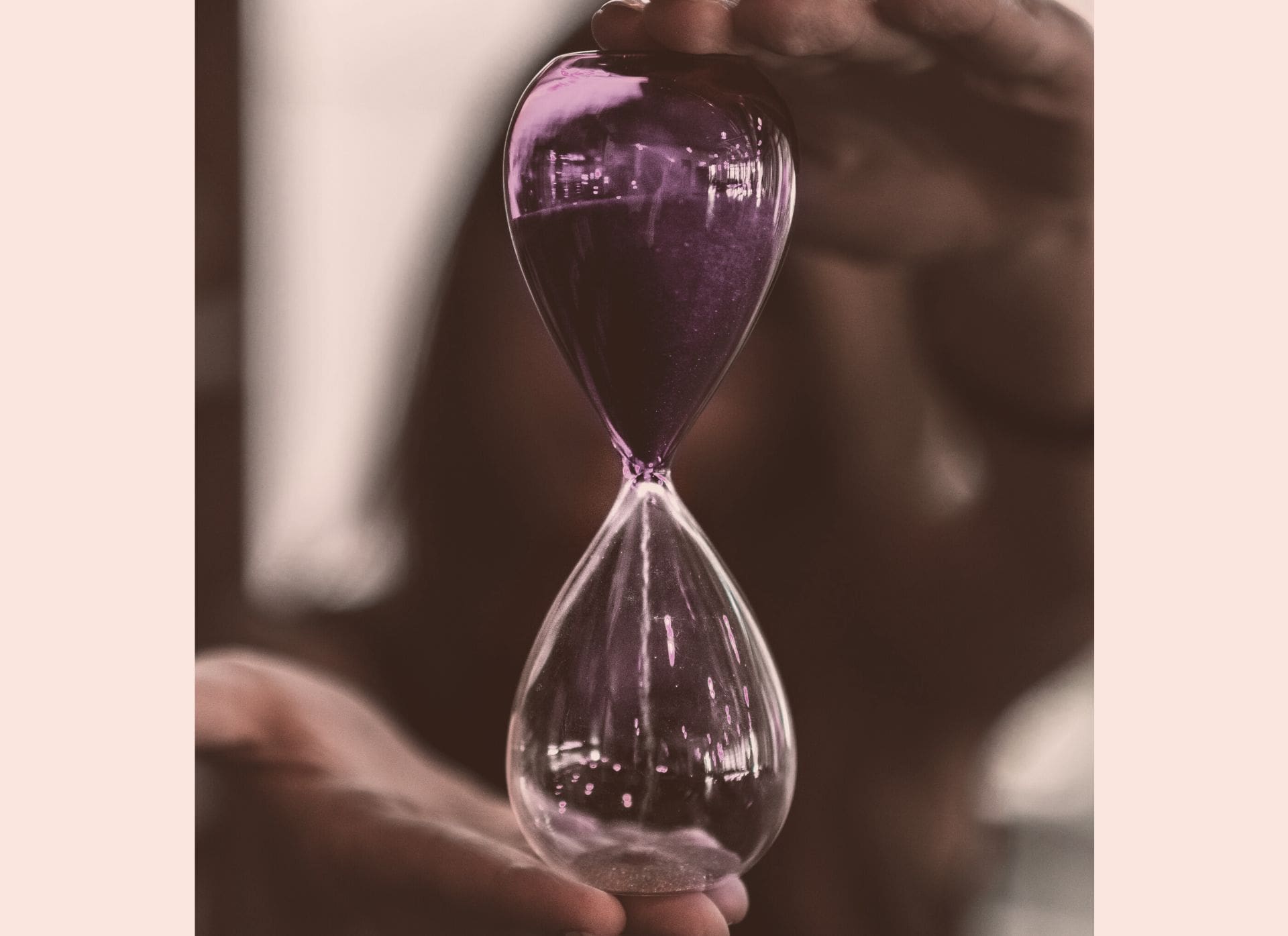 Personne tenant un sablier violet devant son visage